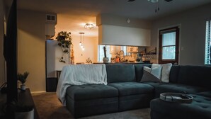 Un salon avec un canapé d’angle, une table basse et une plante.
