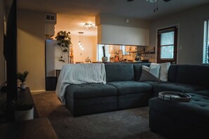 Ein Wohnzimmer mit einem Ecksofa, einem Couchtisch und einer Pflanze.