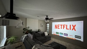 Un salon doté d’un grand écran affichant le logo de Netflix, d’un ventilateur de plafond et d’un design moderne.