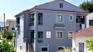 Un edificio a più piani con balconi, una scala visibile e un cartello che indica che si tratta di un albergo.