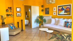 Un soggiorno luminoso e giallo con un divano, un tavolo da pranzo e un angolo cottura.