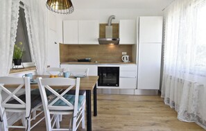 Une cuisine moderne avec des meubles blancs, un plan de travail en bois et un four encastré.