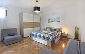 Une chambre à coucher comprenant un lit, un canapé, une armoire, une table de chevet et une plante en pot.
