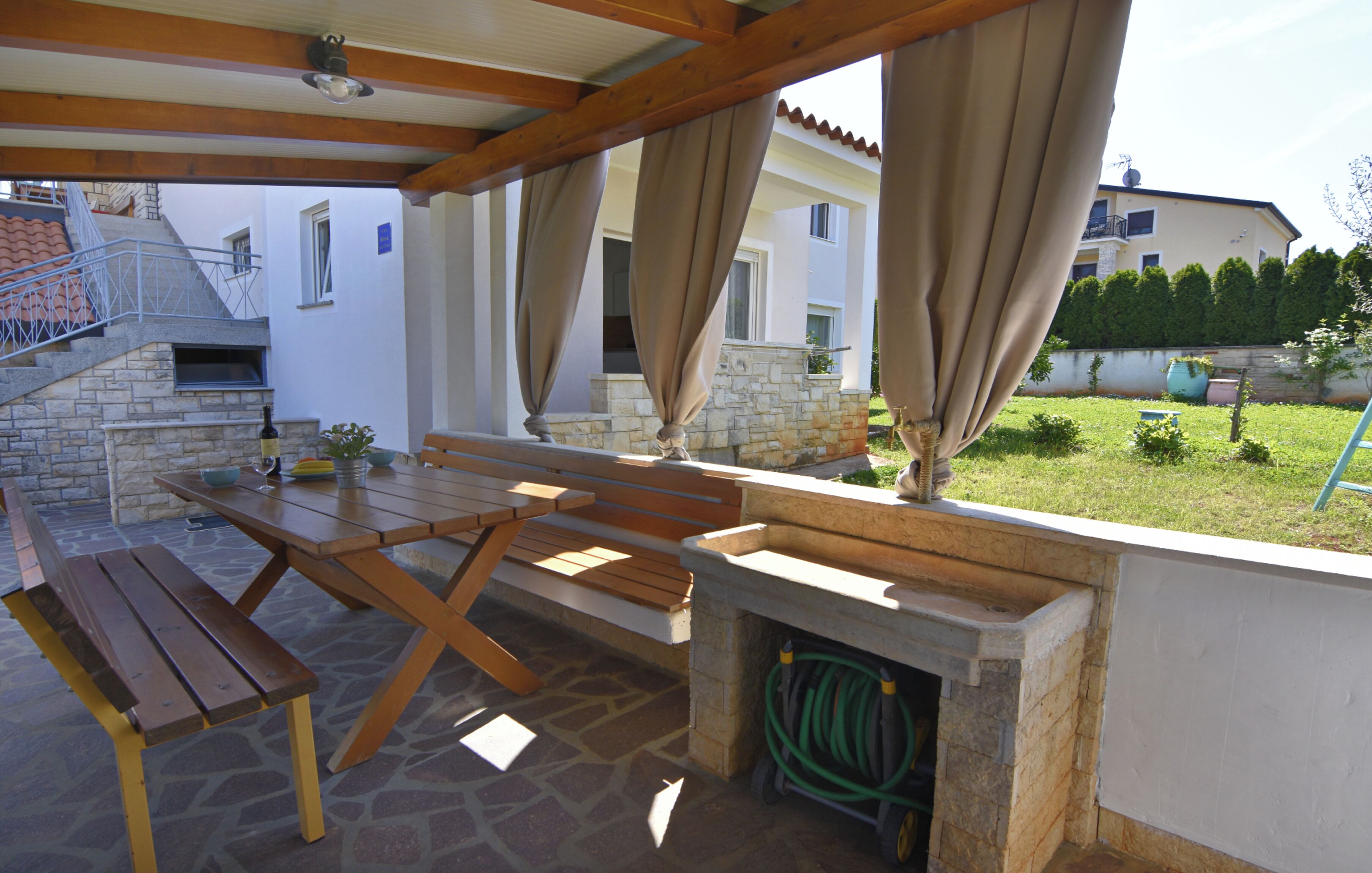 Eine Außenpatio mit Steinboden, Holzbanken und einem Steinkamin.