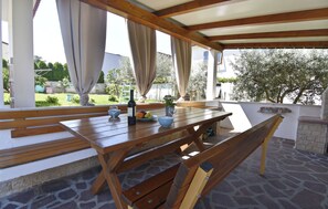 Une terrasse extérieure avec une table en bois, des bancs et un sol en pierre.