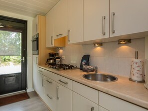 Een moderne keuken met witte kastjes, roestvrijstalen apparatuur en een ingebouwd spoelgedeelte.