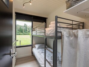 Een slaapkamer met stapelbed, raam, deur en een plafondlamp.