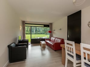 Een moderne woonkamer met een rode bank, een witte eettafel en een zwarte stoel.