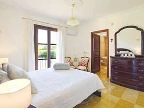 A bedroom with a bed, a dresser, a mirror, a lamp, and a view of the outdoors. - Tranquil Binissalem Country Home With Pool (Binissalem)