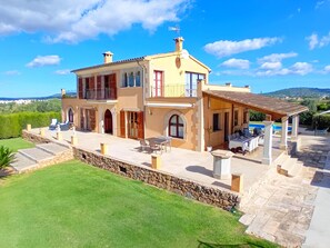 A two-story house with a stone retaining wall, outdoor seating, and a pool. - Tranquil Binissalem Country Home With Pool (Binissalem)