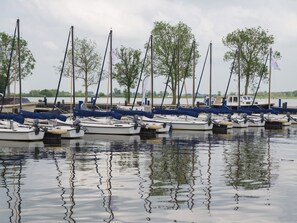 A marina with several boats docked, trees in the background, and calm water. - HouseBoat MeerRand by Interhome (Offingawier)