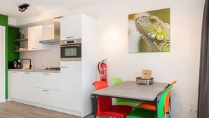 Eine moderne Küche mit weißen Schränken, einem eingebauten Backofen und einem Essbereich mit Tisch und bunten Stühlen.