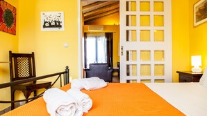 Una habitación de hotel con una cama, una silla, un escritorio y una puerta que da a otra estancia.