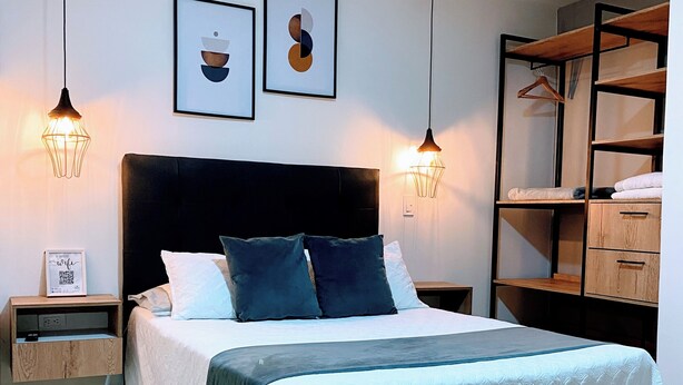 A modern bedroom with a bed, bedside tables, a wardrobe, and wall art.