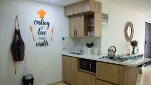 A kitchen with wooden cabinets, a stainless steel sink, a kettle, and a wall-mounted sign.