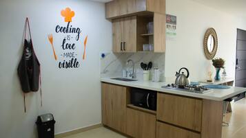 A kitchen with wooden cabinets, a stainless steel sink, a kettle, and a wall-mounted sign.