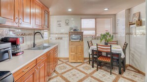A kitchen with wooden cabinets, a microwave, a sink, and a dining table with chairs. - Stylish Stay in Condesa for Football Fans (Mexico City)