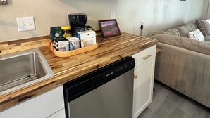 Una cocina equipada con lavavajillas, cafetera y encimera de madera.