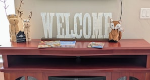 Un comptoir d’accueil orné d’une grande pancarte « BIENVENUE », d’un ours en peluche, d’un jouet en peluche représentant un renard et de quelques magazines.