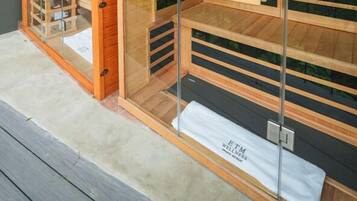 A modern wooden structure with glass walls, a bench, and a view of a landscape.