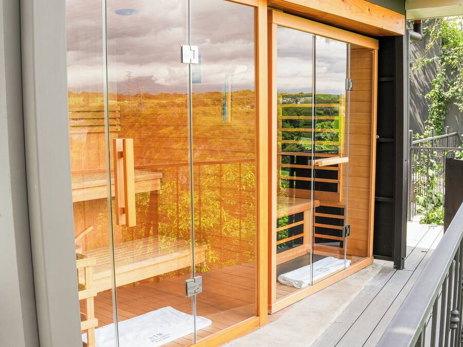 Une terrasse en bois avec une paroi vitrée, un banc en bois et une vue sur un paysage verdoyant.