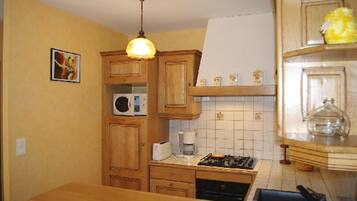 A kitchen with wooden cabinets, a microwave, a gas stove, and a hanging light fixture.