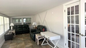 A compact living space with a sofa, a small table, and a door with glass panels. - Spacious Furnished Retreat- Perfect for Extended Stays (Venice)