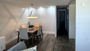 A modern dining area with a wooden table and chairs, a hanging light fixture, and a staircase leading to another level. - Spacious Furnished Retreat- Perfect for Extended Stays (Venice)
