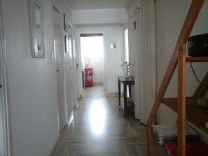 Ein Flur mit Holzboden, weißen Wänden und einer Tür am Ende.