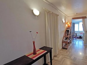 Ein Flur mit einem Tisch, einer Blumenvase und einer Treppe, die in einen Essbereich führt.
