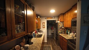 Une cuisine avec des meubles en bois, un réfrigérateur en acier inoxydable et un plan de travail en granit.