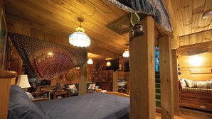 Une pièce chaleureuse avec un lit, des murs en bois, une tapisserie et une pancarte sur laquelle on peut lire : « Repaire d’hobbit ».