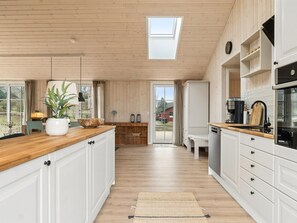 Una cocina amplia con armarios de madera, una isla grande y un tragaluz.