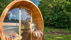 A wooden, circular, glass-enclosed structure with a bench and table inside. - "Martta" - 250m from the sea by Interhome (Knebel)