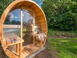 Una estructura circular de madera con paredes de vidrio, que contiene un banco y una mesa.