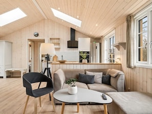 Un interior moderno con techo de madera, un sofá, una mesa de centro y un comedor.