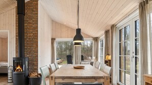 A modern interior with a large wooden dining table, a fireplace, and large windows. - "Martta" - 250m from the sea by Interhome (Knebel)
