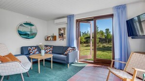 Ein Wohnzimmer mit einer Couch, Sesseln, einem Couchtisch und einem Fernseher.