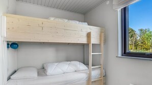 Ein Etagenbett mit einer Leiter, ein Fenster mit Blick auf Bäume und eine Heizung.