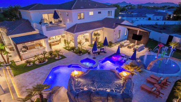 Ein Wohnhaus mit Swimmingpool, Sitzgelegenheiten im Freien und einem angelegten Garten.