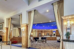 Een hotel lobby met een bar, houten lambrisering en een kamerbreed tapijt met dessin.