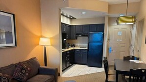 A compact living space with a sofa, a dining table, and a kitchenette. - 110 - Next to Disney - Pool (Orange County)