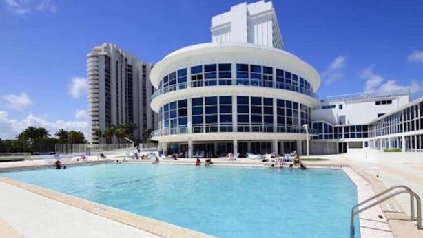 Ein modernes Gebäude mit Poolbereich, ausgestattet mit einem großen, runden Pool und blauem Himmel.