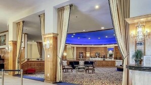 Eine Hotelhalle mit Barbereich, Holzvertäfelung und einem gemusterten Teppich.