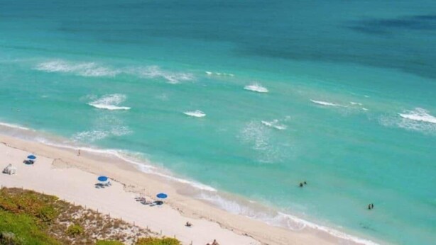 A beach with clear turquoise water, a sandy shore, and a few umbrellas. - 530 - Large Studio Ocean View (Miami Beach)