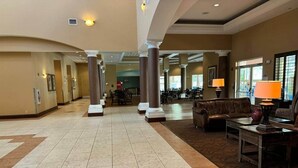 A spacious lobby with a tiled floor, columns, a sofa, and a table with a lamp. - 510 - Oasis in Disney world (Orange County)