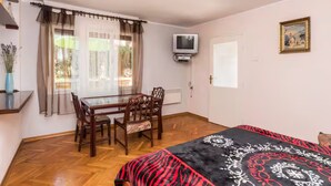 A room with a bed, a TV mounted on the wall, a dining table with chairs, and a window with curtains. - Cozy Holiday Studio in Umag (Umag)