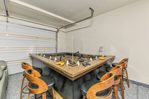 Une salle de conférence équipée d’une grande table, de quatre chaises en bois et de divers appareils électroniques posés sur la table.
