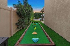 A narrow outdoor area with artificial turf, a wooden bench, and a hedge. - The Ultimate Oasis: 7BR Private Resort, Spa & More (Coachella)