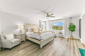 A bedroom with a bed, a chair, a nightstand, a ceiling fan, a window with curtains, and a potted plant. - The Ultimate Oasis: 7BR Private Resort, Spa & More (Coachella)
